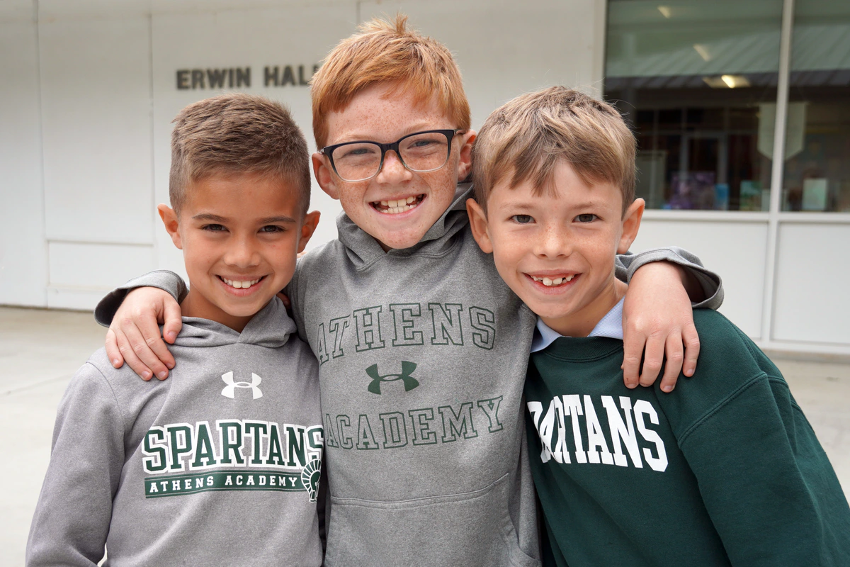 Three Athens Academy students smiling together outside Erwin Hall